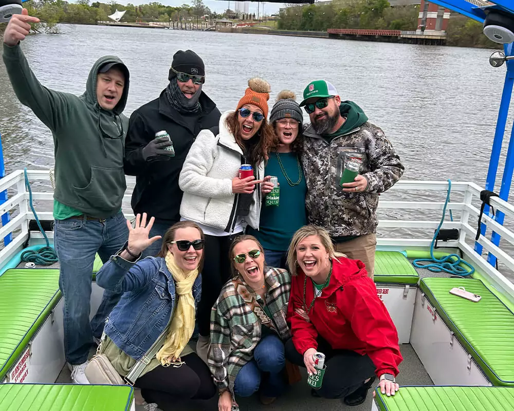 friends laughing and waving to the camera on a pedal cruise